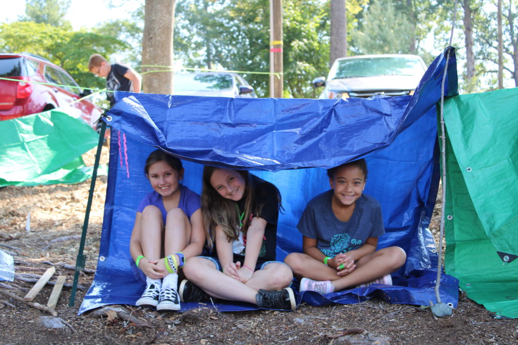 From left to right, Sierra Wood, Summer Chester and Zoe Woods sit together under their tarp shelter at a Caldwell County 4-H 2019 Summer Exploring class, where youth learned outdoor survival skills from the County Emergency Response Team. Youth their age enjoy belonging and working in groups.