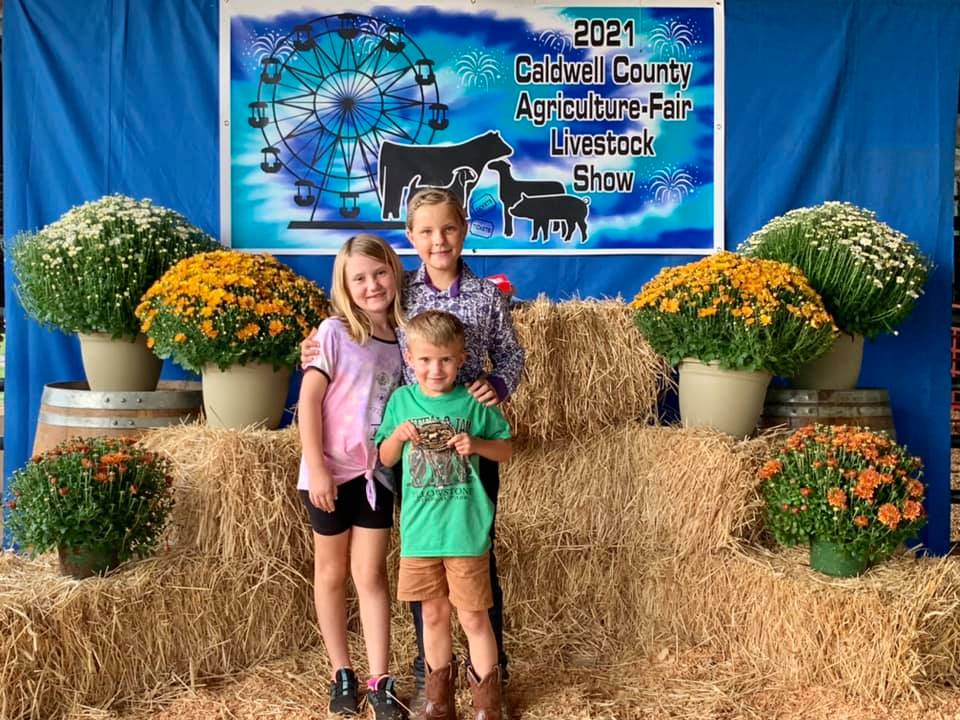 Shelby and Harrison Ford pose with Peyton Taylor and the Caldwell Agriculture Fair. All three work with and show livestock.
