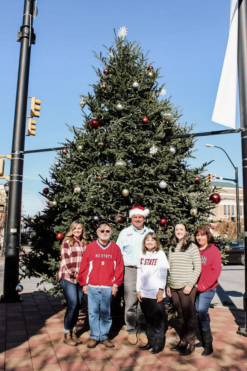 Extension employees pose in front of a tree in downtown Lenoir.