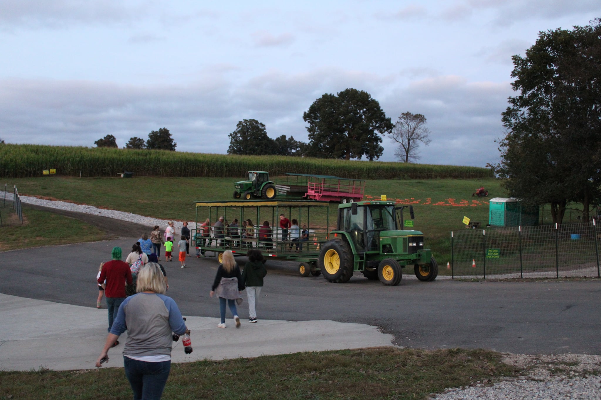 Families get ready to take a ride around Johnny Wilson Farm during fall 2021. There's a pumpkin patch, corn maze and tractors parked outside.