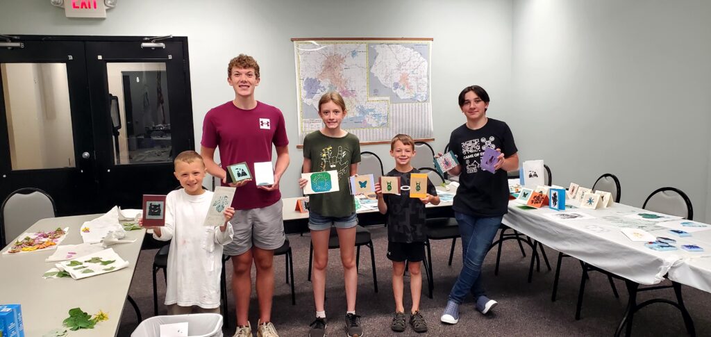 Participants of Art Camp pose proudly with their artwork. From left to right, Joseph Penny, Ellis Waites (Junior Leader), Emma Combs (Junior Leader), Rhett Coffey, and Caleb Schwartz (Junior Leader).