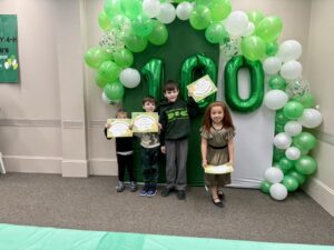 4 small children standing in front of green and white balloons