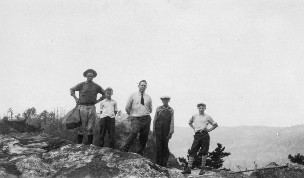 3 boys and two men stand of a rock in Edgemont.